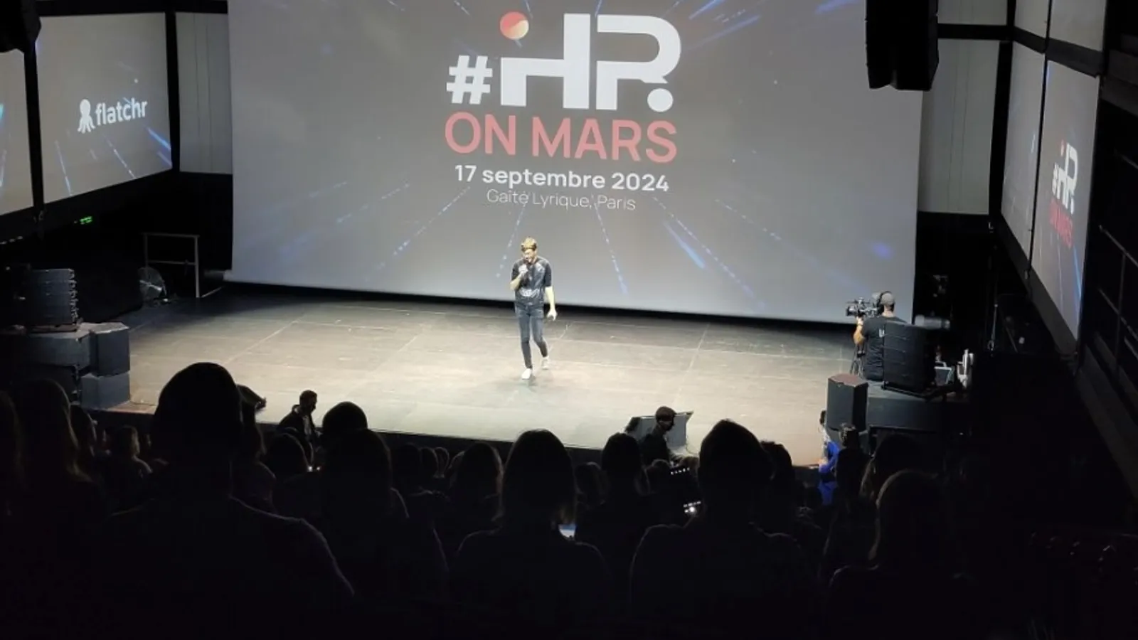 La scène de la Gaîté Lyrique le 17 septembre 2024 : une intervenante devant l’écran annonçant HRonMars 5.1, face au public.